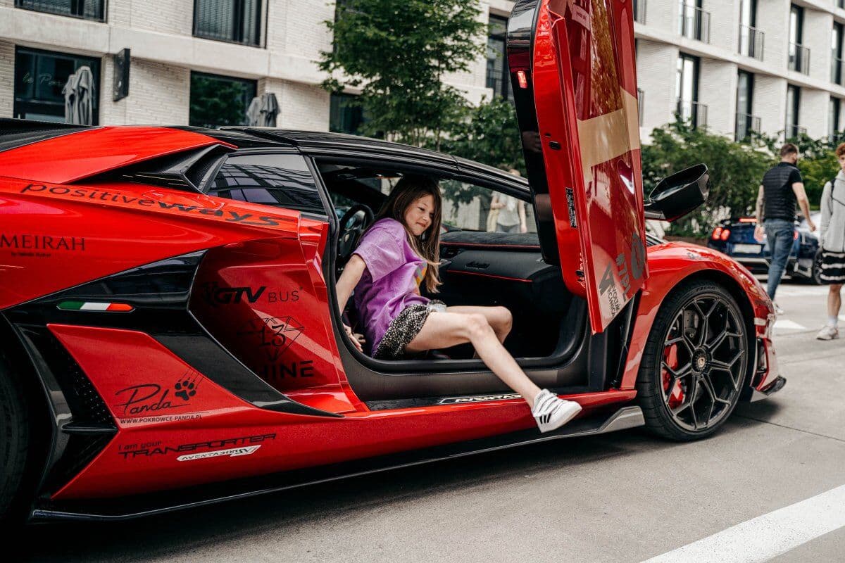 Uczestniczka wysiada z czerwonego Lamborghini z otwartymi drzwiami